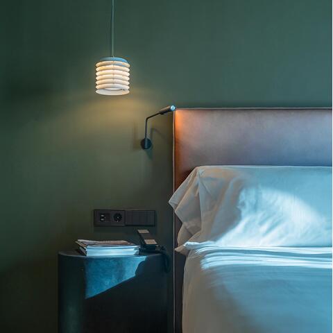 A bed and bedside table in front of a green wall