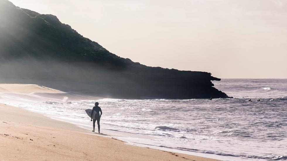 A surfer strolls along Bells Beach, Victoria, Australia