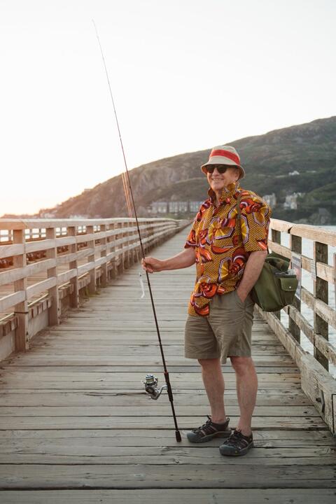 A fisherman in a Hawaiian shirt on the pire poses for the camera 