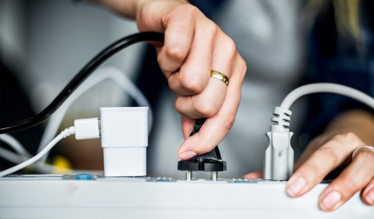 A person practicing electrical safety by using a surge protector.