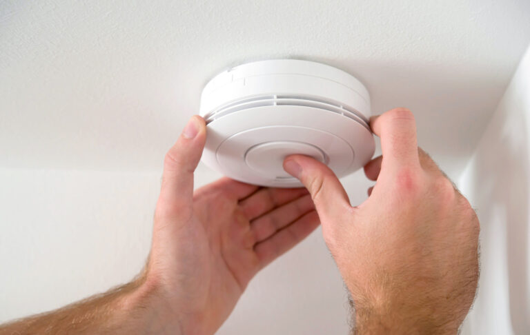 A person installing a smoke detector for increased home safety.