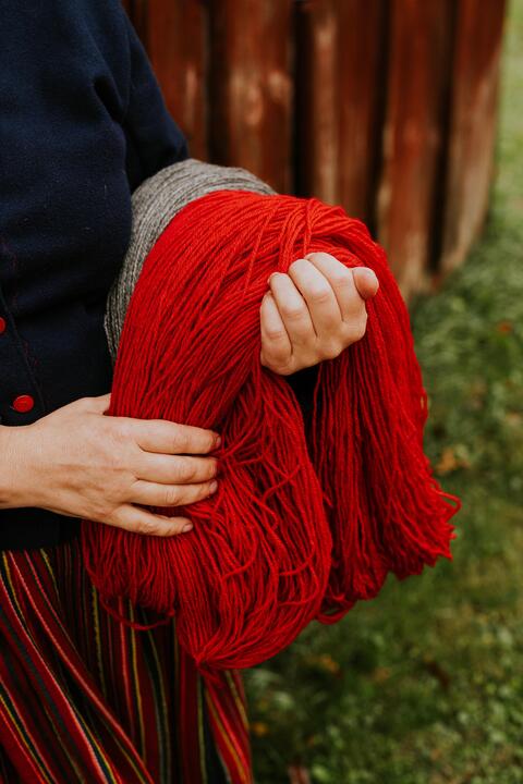 Bright red yarn laid across a women's hand