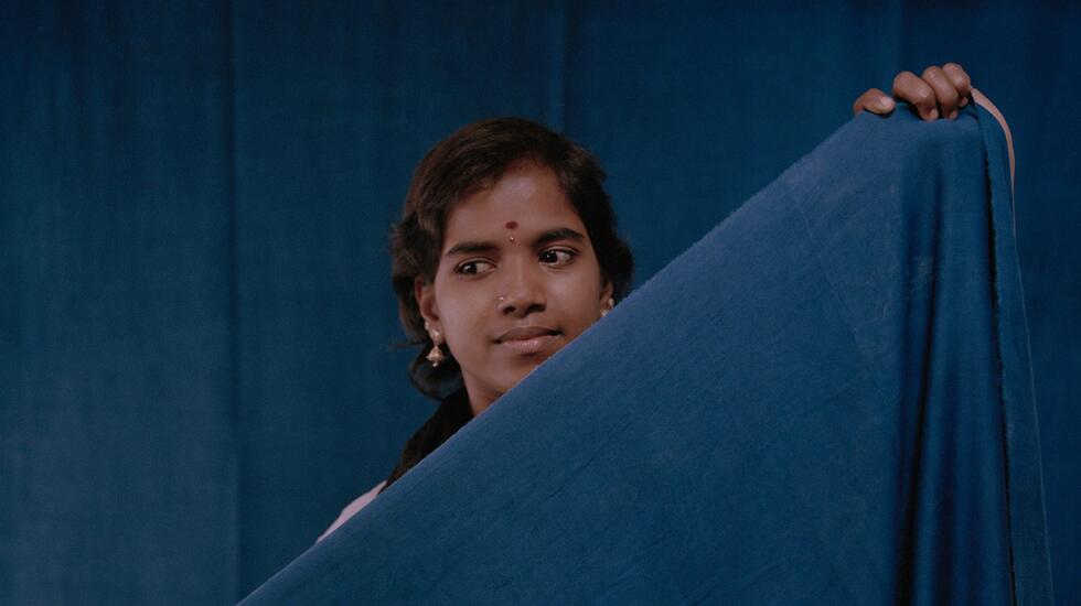 A female member of staff at The Colours of Nature, Tamil Nadu, India holds a piece of indigo-dyed fabric